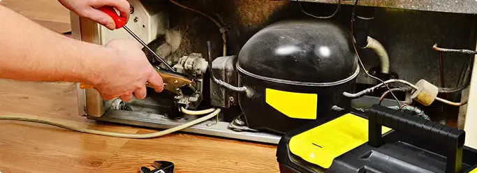 Refrigerator repair technician fixing the compressor and wiring in Helotes, TX