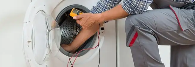 Dryer repair technician inspecting and repairing a clothes dryer in San Antonio, TX
