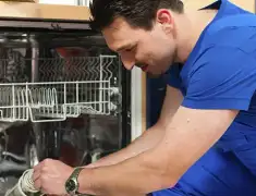 Dishwasher repair technician inspecting and servicing an open dishwasher in San Antonio, TX