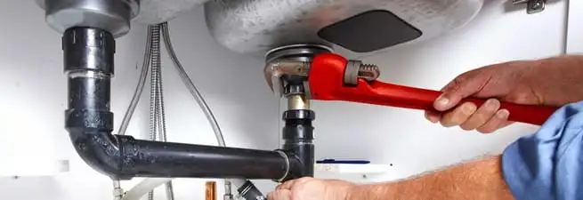 Garbage disposal repair technician tightening the sink drain and disposal connection in San Antonio, TX
