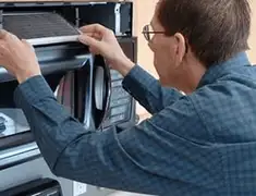 Appliance repair technician replacing a microwave vent filter in San Antonio, TX