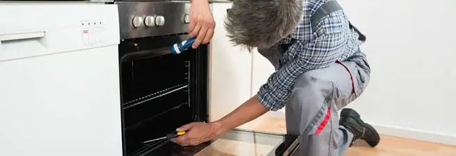 Oven repair technician inspecting and servicing an electric oven in San Antonio, TX
