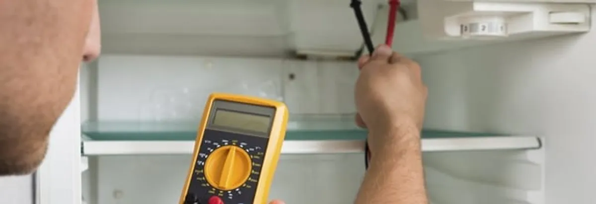 Refrigerator repair technician testing electrical components with a multimeter in San Antonio, TX