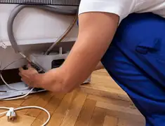 Appliance repair technician fixing refrigerator water line and connections in San Antonio, TX