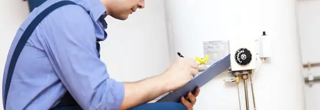 Water heater repair technician inspecting the unit and recording service notes in San Antonio, TX