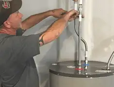 Water heater repair technician tightening supply line connections in San Antonio, TX
