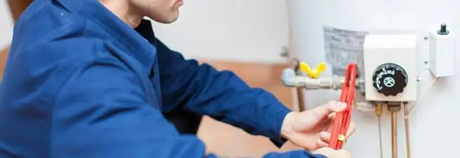 Water heater repair technician adjusting the temperature control and gas valve in San Antonio, TX